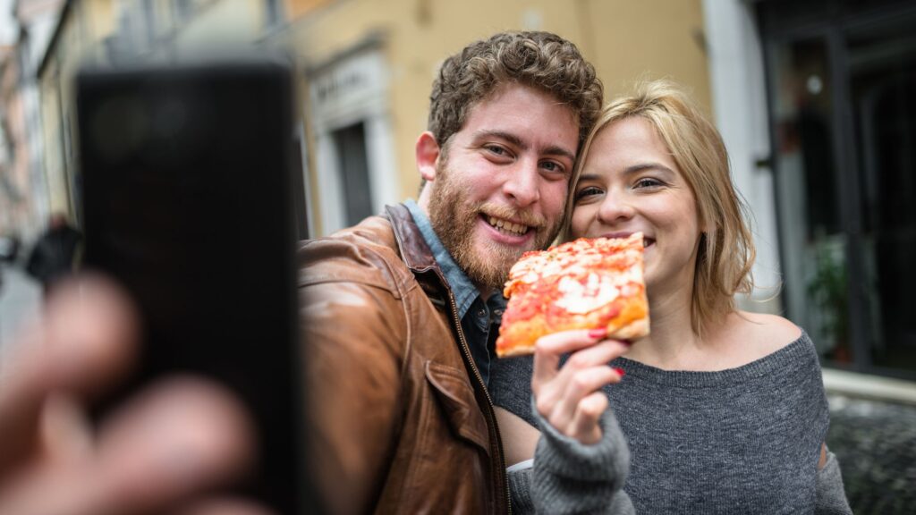 Un ragazzo e una ragazza che fanno la selfi con la pizza